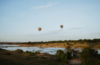 Hot air balloons over a river at sunrise, Tanzania, Yellow Zebra Safaris