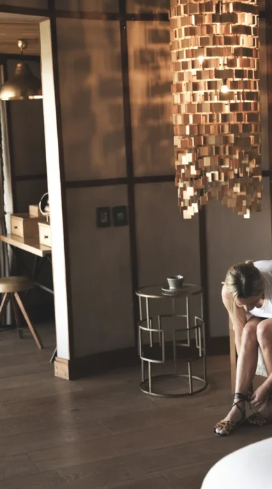 Lady tying her shoes in living room, Mombo, Moremi Game Reserve, Botswana - Yellow Zebra Safari