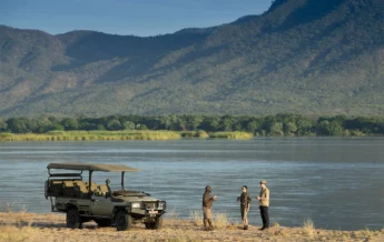 Guests and guide enjoy a drink alongside the water, Nyamatusi Camp, Zimbabwe - Yellow Zebra Safaris