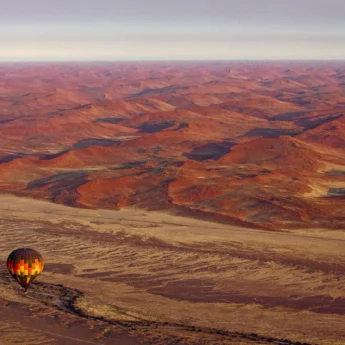 Hot air balloon floats over the dunes, Little Kulala, Sossusvlei, Namibia - Yellow Zebra Safari