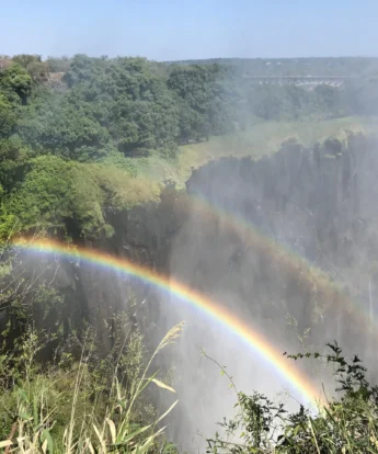 A rainbow shines over a sliver of Victoria Falls, Zambia - Yellow Zebra Safaris