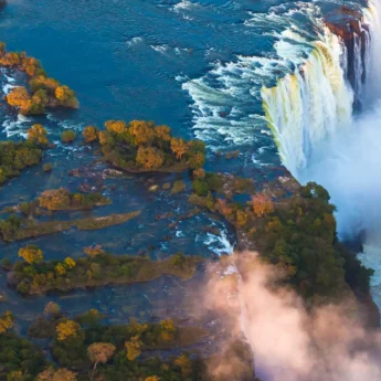 Aerial shot of Victoria Falls right at the edge as plumes of water spray come up - Yellow Zebra Safaris