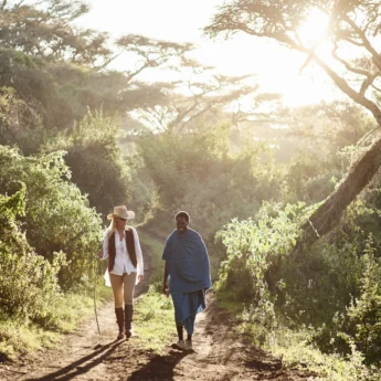 A guest and a guide walk in lush greenery, Serengeti, Tanzania - Yellow Zebra Safari