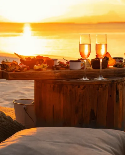 Sun shines through champagne glasses on a table on the beach, Zuri Zanzibar, Tanzania - Yellow Zebra Safari