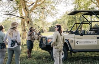 Guide and guest stand by safari vehicle for a coffee stop, Chicari, Gorongosa, Mozambique - Yellow Zebra Safaris