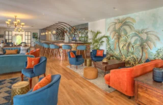 Lounge and bar with brightly coloured blue and orange couches at Latitude 0 Degrees, Kampala, Uganda - Yellow Zebra Safaris